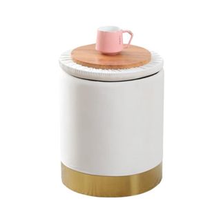 A cream storage ottoman with a pink mug on top