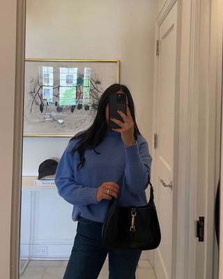 A woman taking a mirror selfie and holding a Gucci Jackie bag.