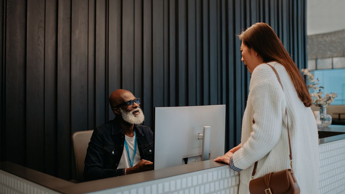 Temporary hiring concept image showing woman signing into office at front desk.