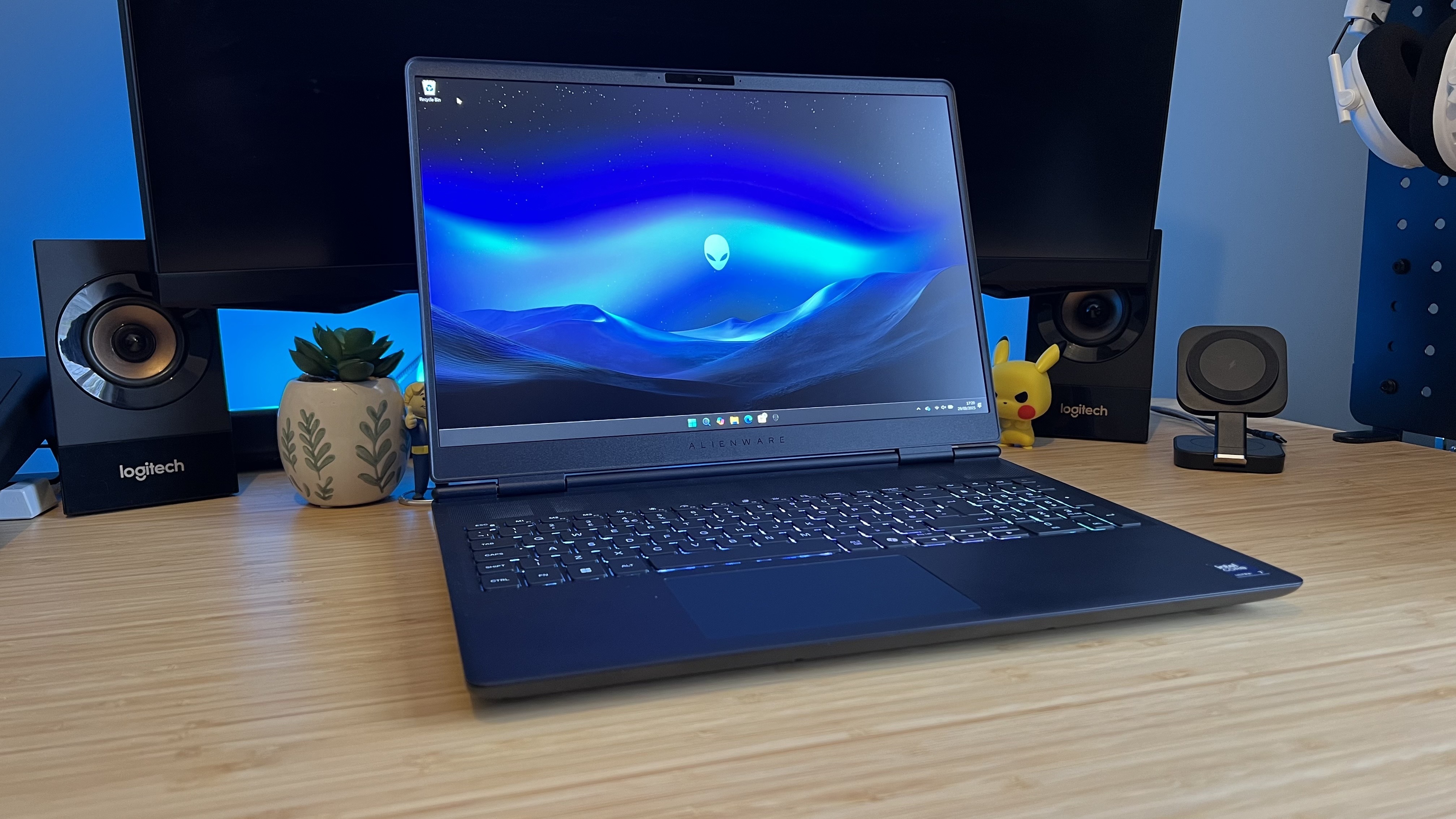 Alienware 16X Aurora gaming laptop on a wooden desk with blue backlighting