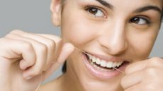 How to floss your teeth: image shows woman flossing teeth