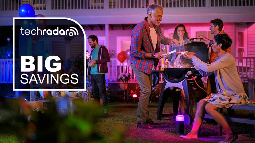 People enjoying a party illuminated by Philips Hue smart lights, with the words &#039;TechRadar Big Savings&#039; overlaid