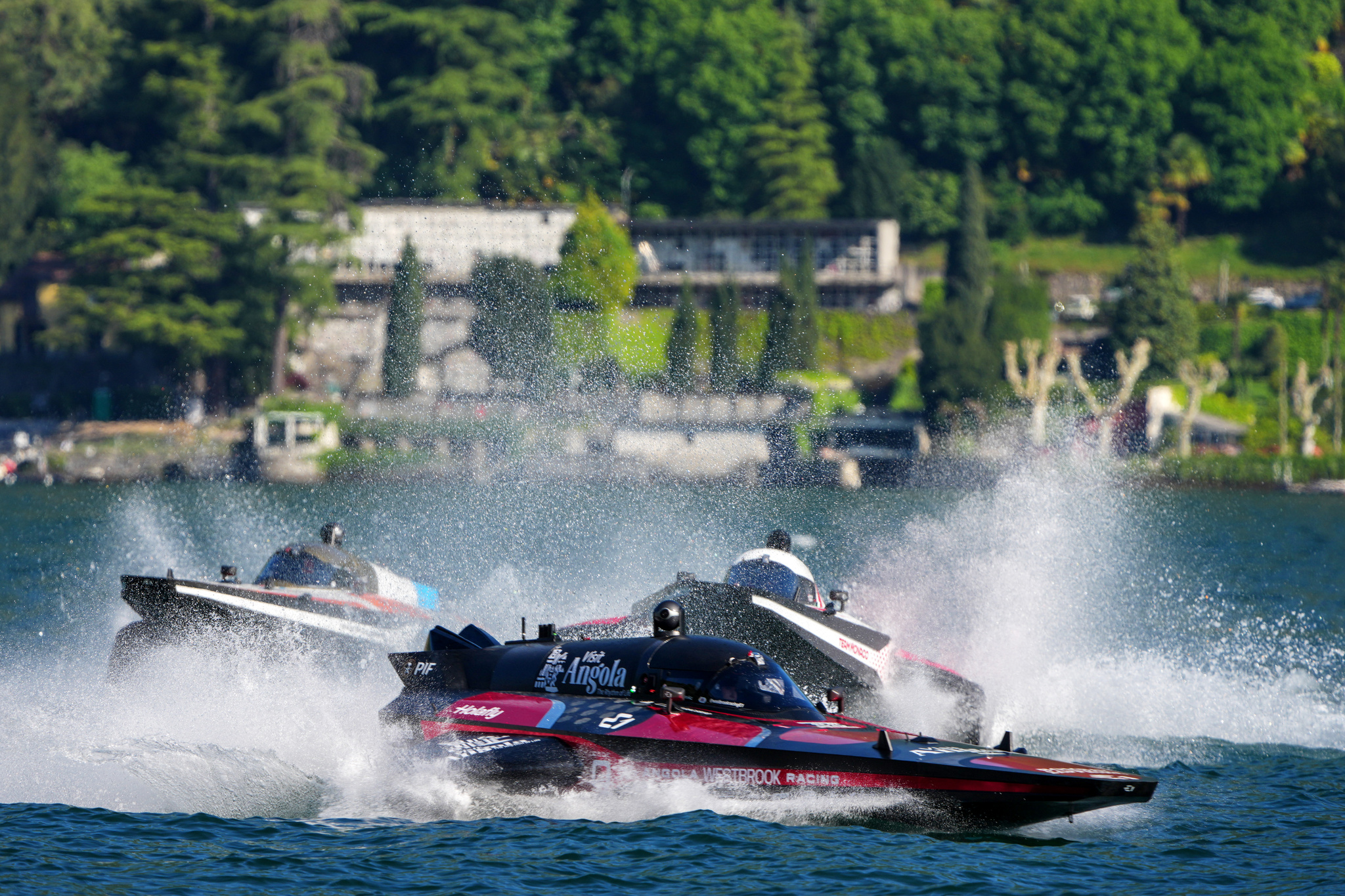 A powerboat speeding along the waters of Lake Como, with italian villas in the background.