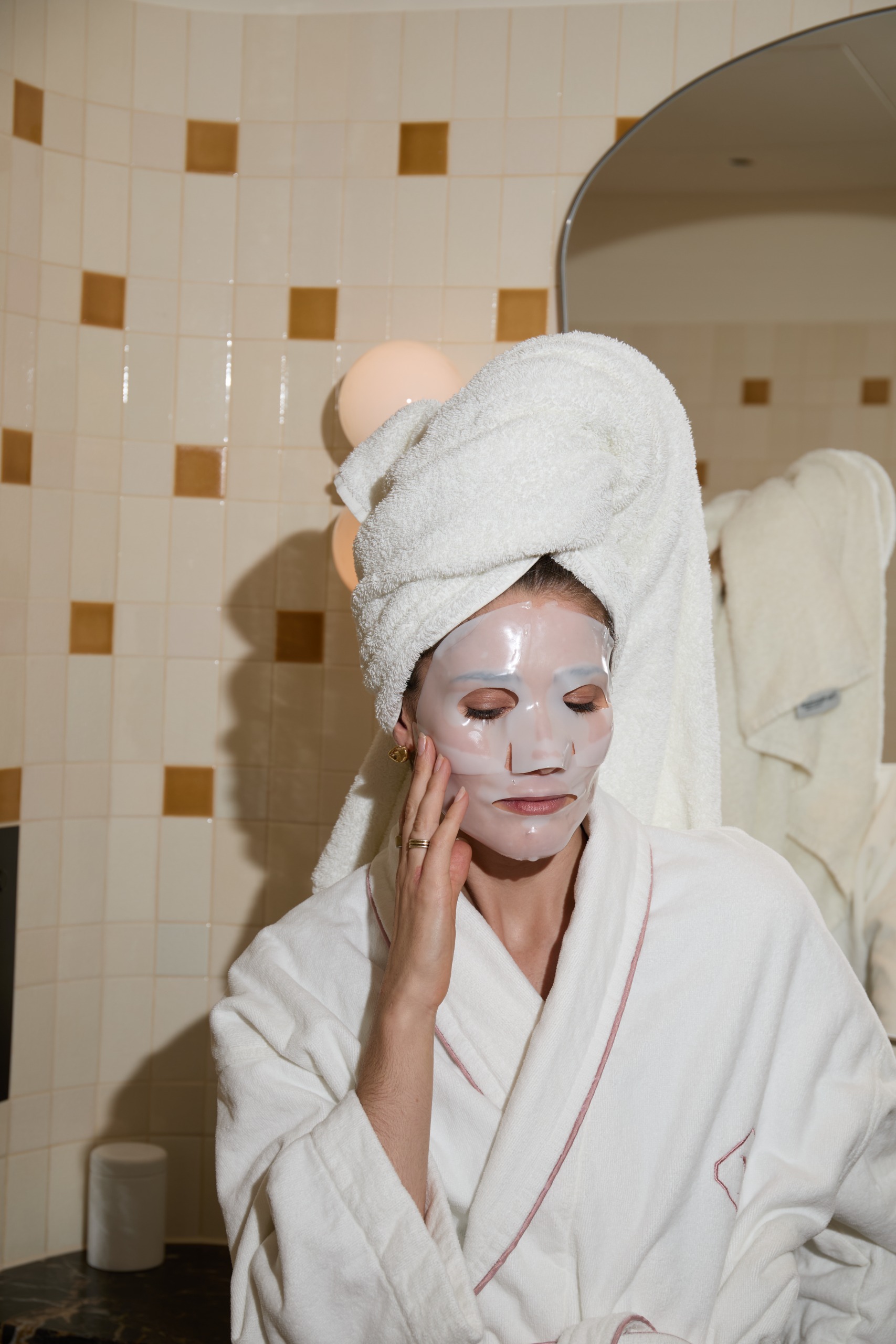 Beauty editor Eleanor Vousden wearing a sheet mask, dressing gown and towel on her head