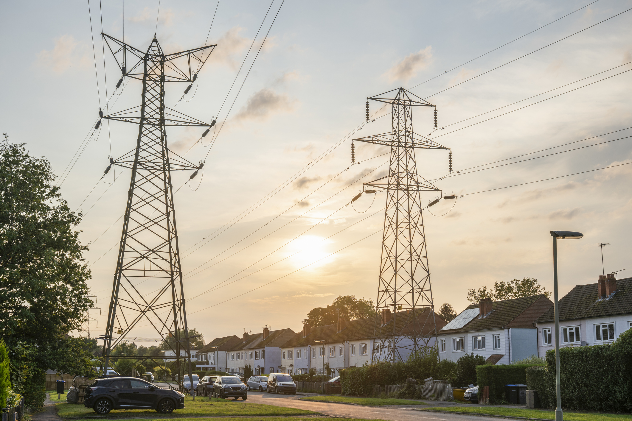 Suburban street with electricity pylons above. Sunset in Surrey, England