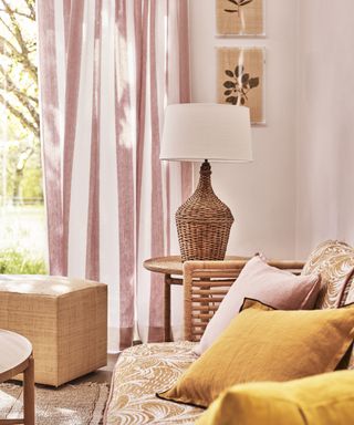 A living room curtain idea with pink and white striped fabric and yellow and rattan accessories