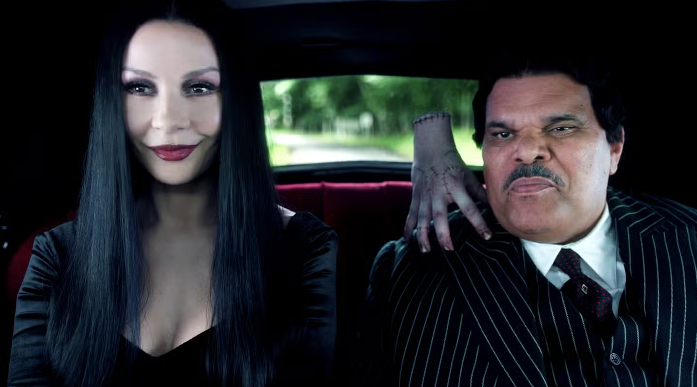 Catherine Zeta-Jones as Morticia and Luiz Guzman as Gomez, with Thing perching on Gomez&#039;s shoulder.