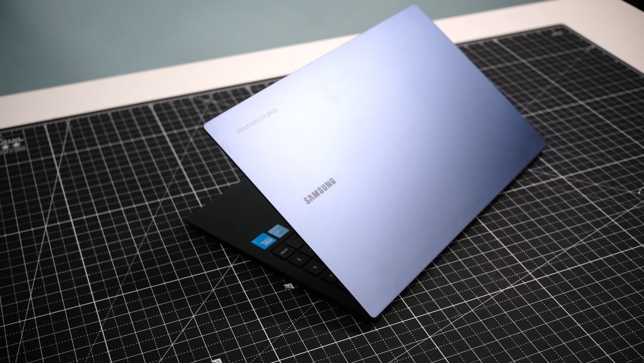 Samsung Galaxy Chromebook Plus open on a black cutting mat showing the lid with Samsung logo