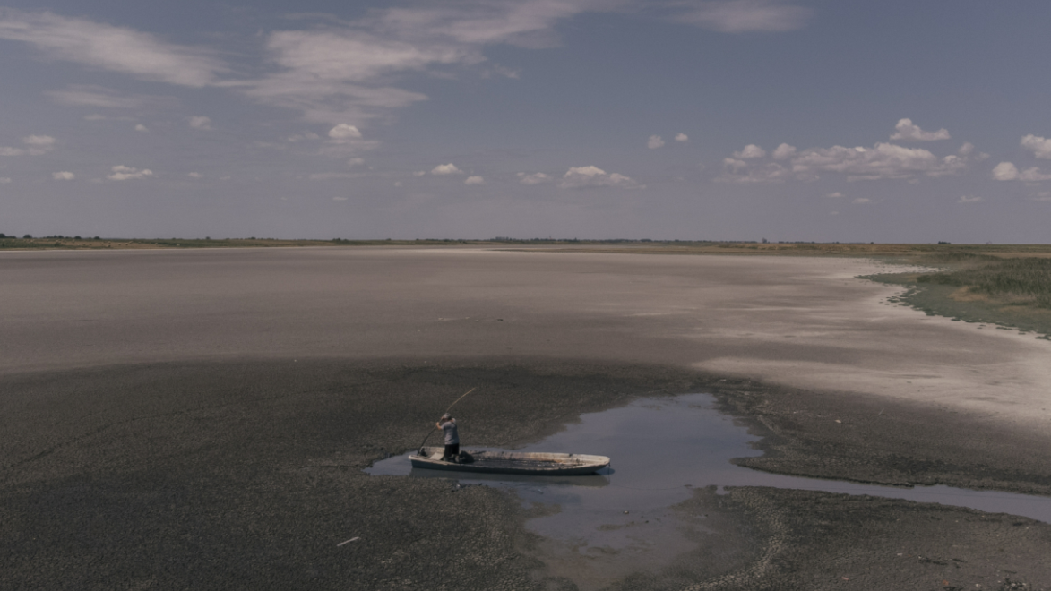 A person in a boat in a dried up lake.