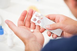 A person opening a blister pack of pills.