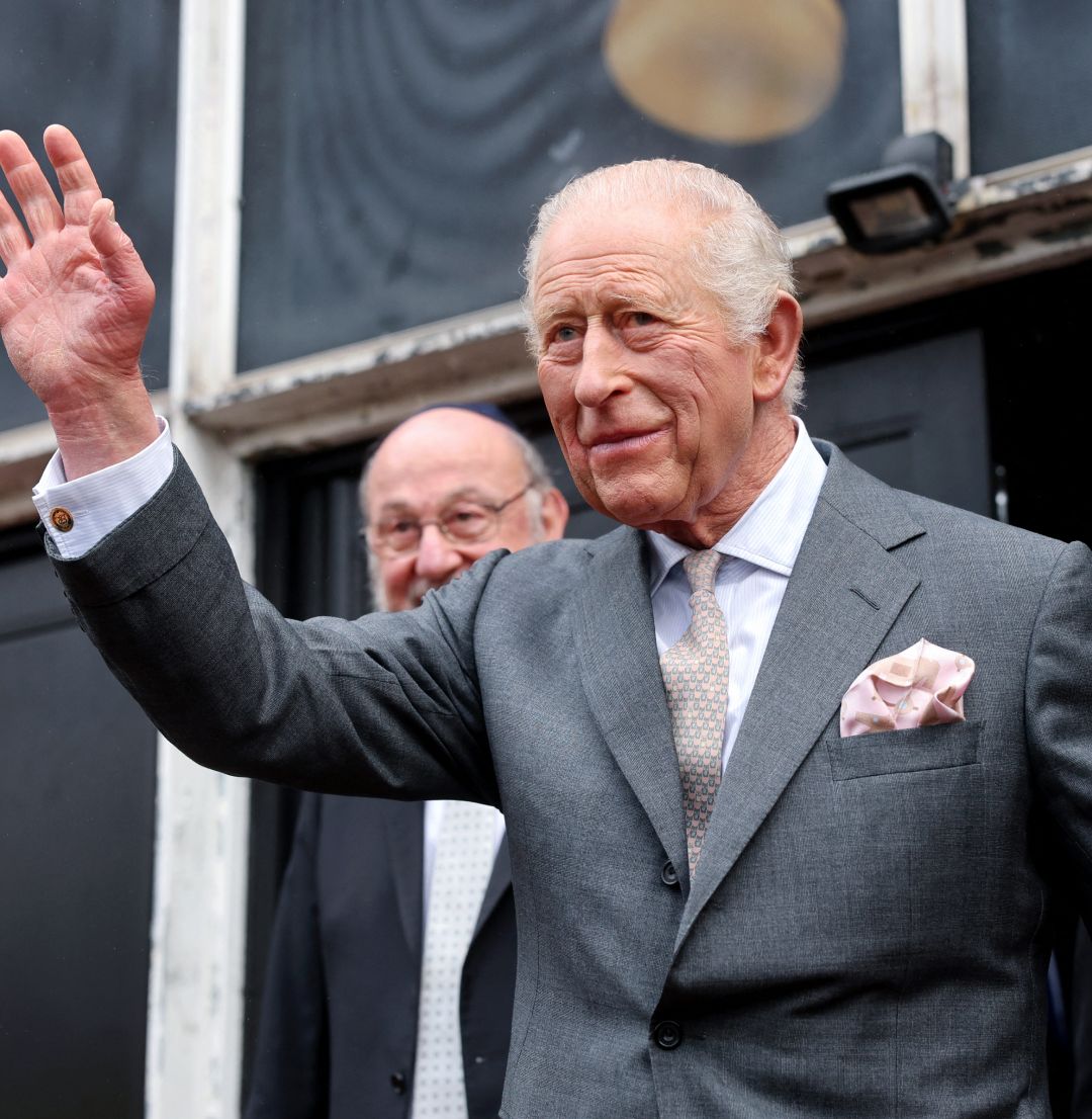 King Charles wearing a gray suit and waving