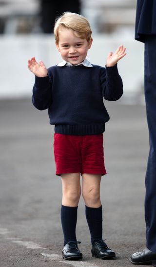 Prince George wearing red shorts and a navy jumper