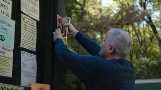 A man stapling up a flyer in Netflix's Into the Fire: The Lost Daughter.