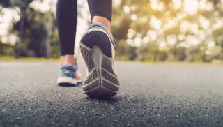 Woman's feet running on road closeup on shoe.