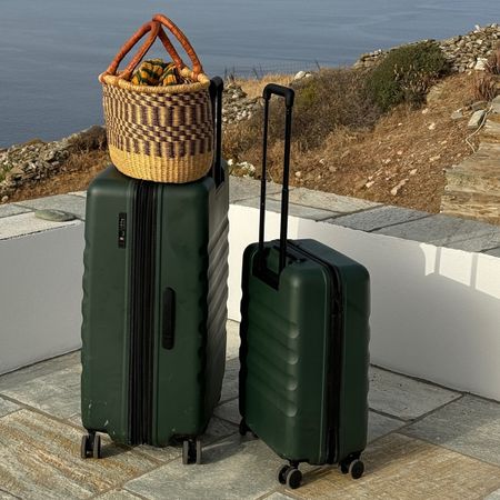 Photo of dark green suitcase and carry-on luggage on balcony overlooking Mediterranean sea.