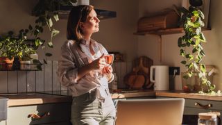 A woman enjoying a cup of tea inside her kitchen