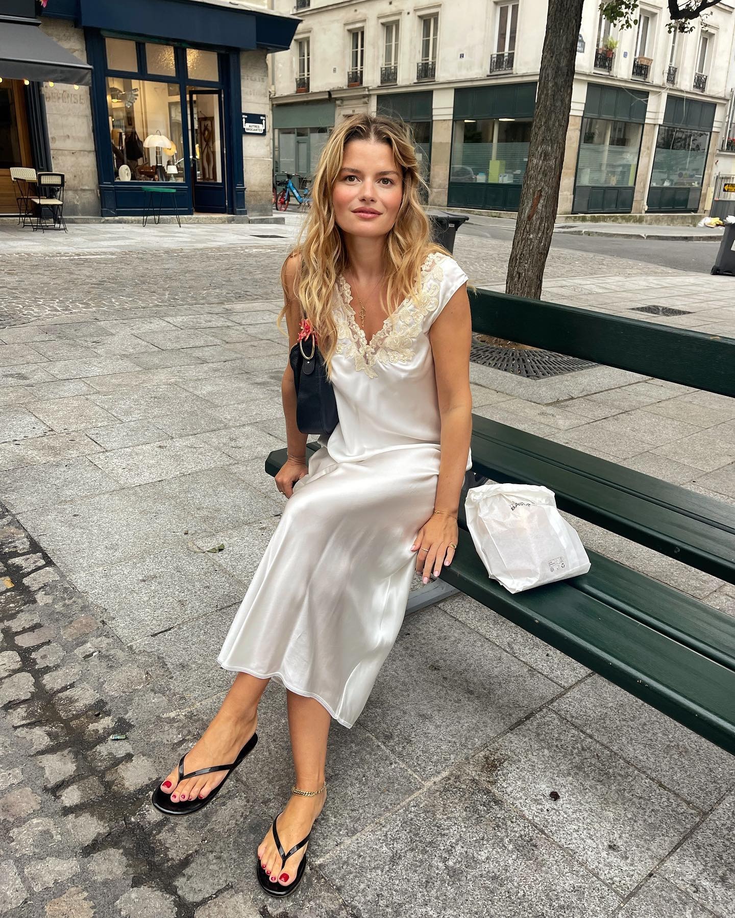 Influencer Sabina wears a white slip dress with black flip flops.