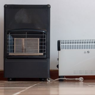 Portable gas heater and electric heater standing side by side