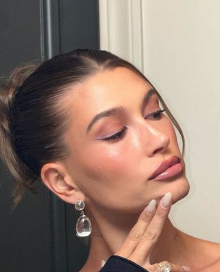 A photo of Hailey Bieber wearing black liquid liner with a pastel purple double-wing.