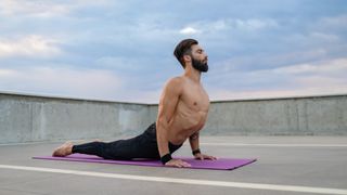 Man on yoga mat during outdoor workout performing upward dog yoga move