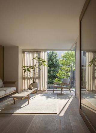 A living room in muted tones, with a large opening that allows lots of light to fall in