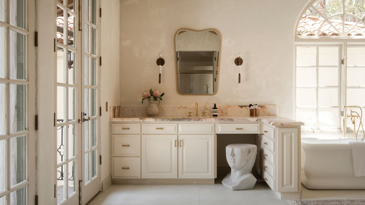 A bathroom with limewash walls, gold hardware and a freestanding bathtub
