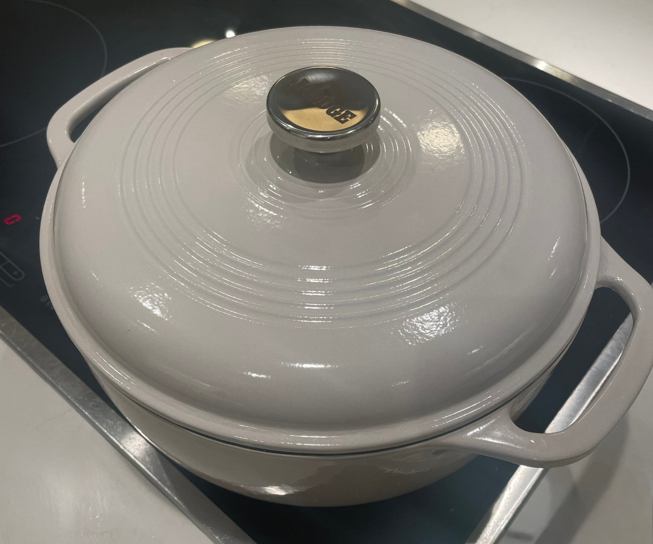A light grey colored Dutch oven on a black stovetop.