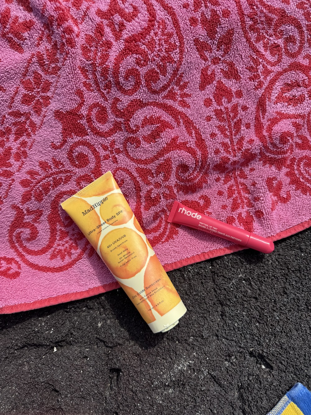 A bottle of MadHippie Body SPF on the beach in Hawaii.