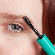A close up of a woman using an eyebrow gel from Thrive Causemetics.