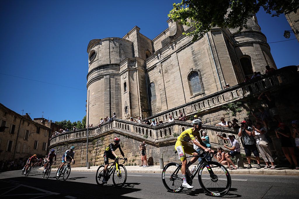 UAE Team Emirates - XRG team's Slovenian rider Tadej Pogacar wearing the overall leader's yellow jersey cycles with the pack of riders (peloton) past the Saint-Etienne church in Uzes during the 16th stage of the 112th edition of the Tour de France cycling race, 171.5 km between Montpellier and Mont Ventoux, southern France, on July 22, 2025. (Photo by Anne-Christine POUJOULAT / AFP) (Photo by ANNE-CHRISTINE POUJOULAT/AFP via Getty Images)