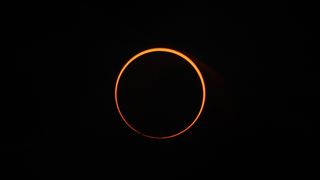 orange ring of light during an annular solar eclipse against a black sky.