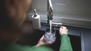 Woman filling up glass at sink