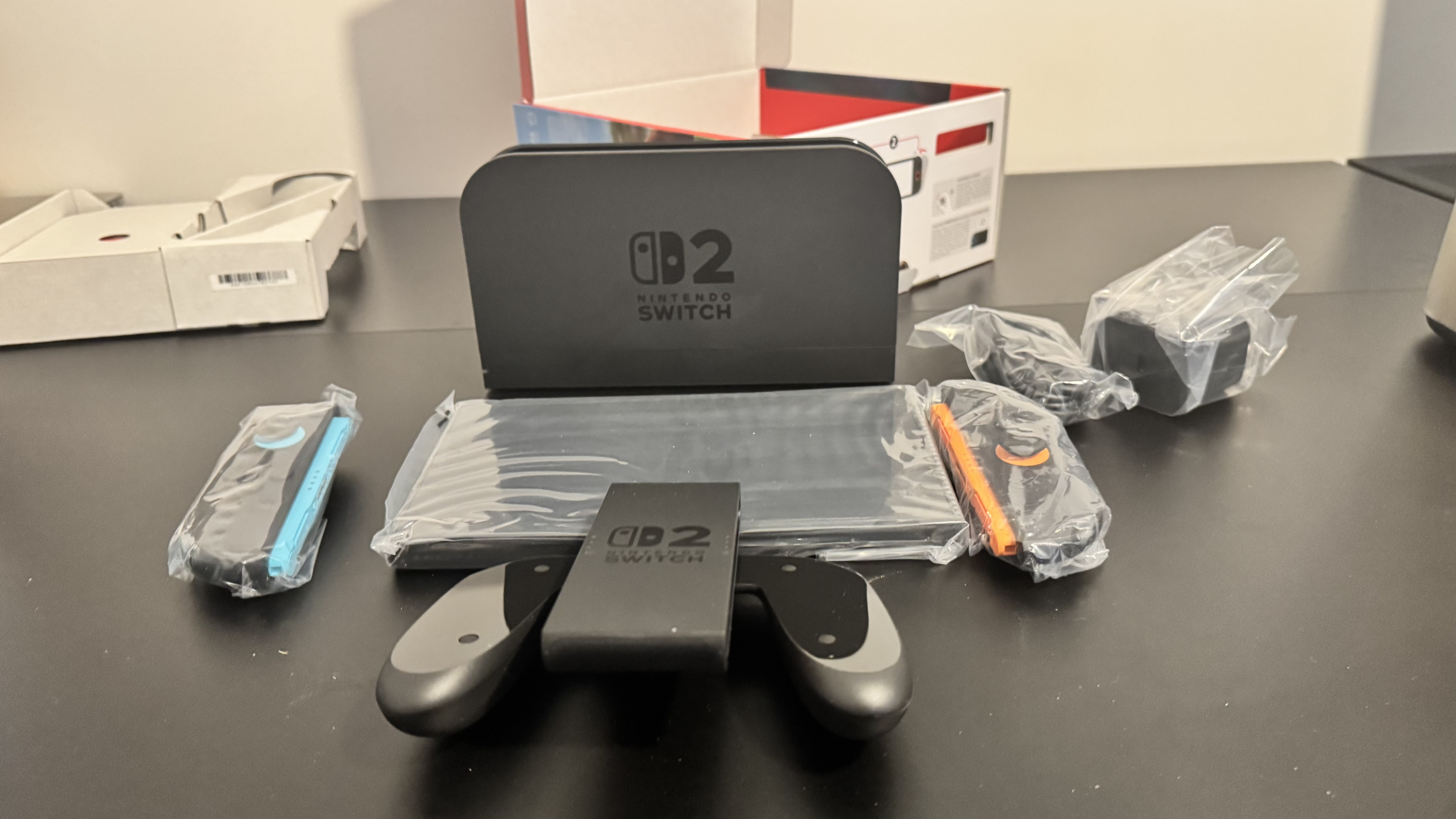 A picture of Nintendo Switch 2 dock with the console in front and the Switch 2 box behind it
