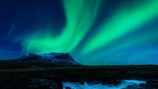 bright green auroras in the sky above a coastal scene in iceland