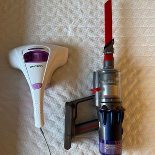 Mattress vacuum on a mattress, next to a dyson handheld vacuum cleaner