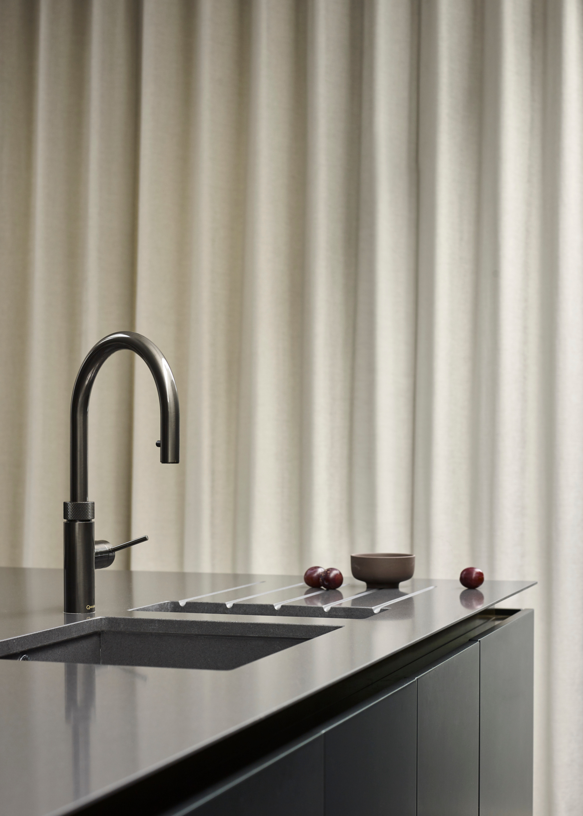a black worktop with a sink built into it and drainage grooves next to the sink