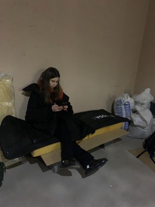 Woman sitting on makeshift bed in Kyiv Ukraine shelter