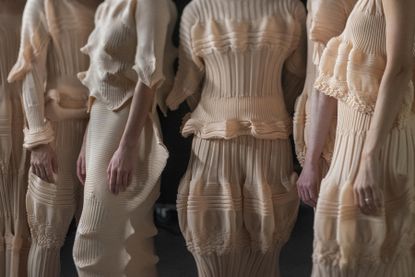 Close up of four women backstage at Issey Miyake by Satoshi Kondo in sculptural pleated dresses