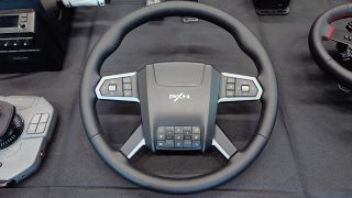 A photo of the new and as yet unreleased PXN Truck wheel surrounded by other racing wheel and flight sim hardware. 