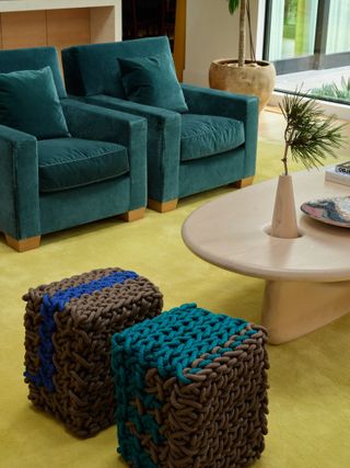 living room with teal armchairs and ottoman, and acid yellow rug and light timber coffee table