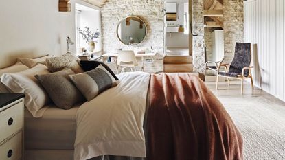 Farmhouse bedroom with stone walls and rust colored bedding