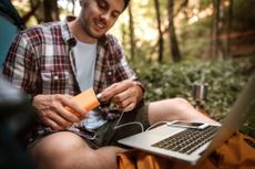 man using a power bank to charge his phone in the woods