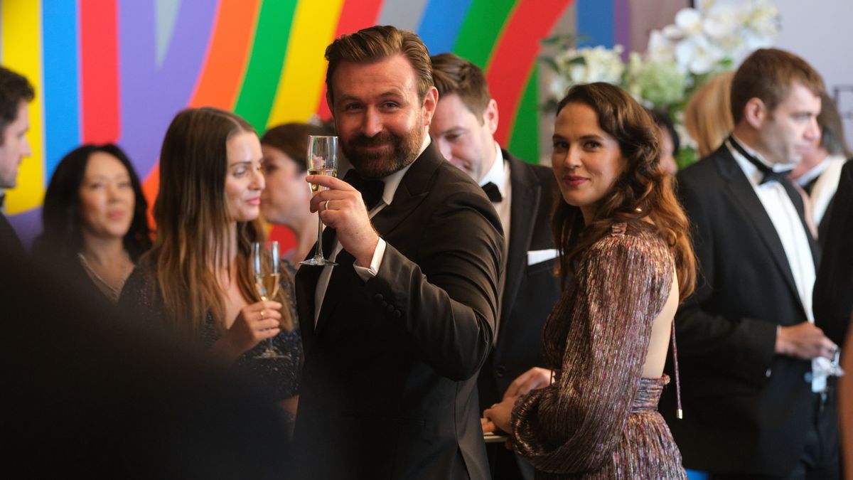 Miles and Lucy at a charity event, smiling in Playing Nice 