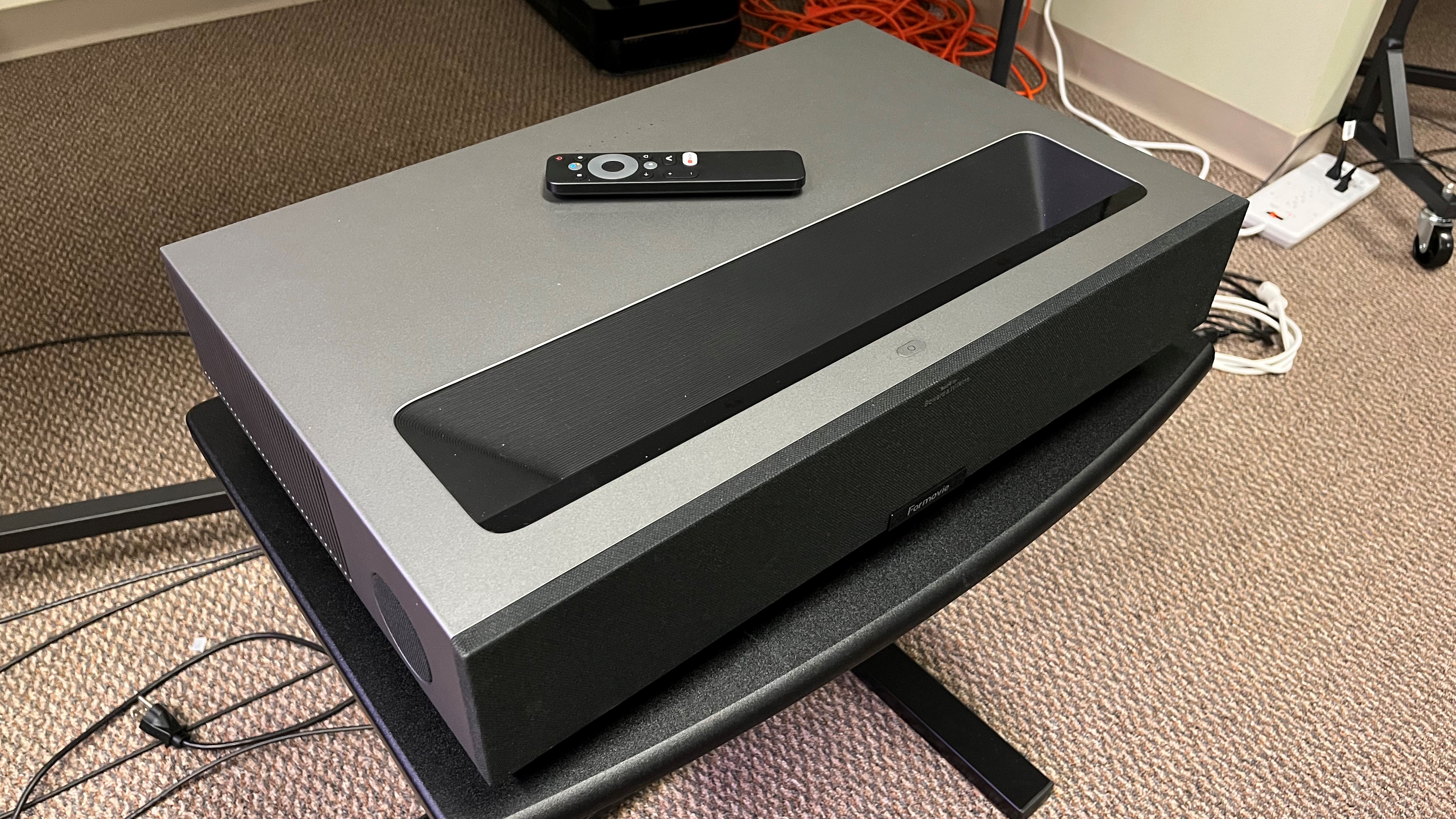 Formovie Theater laser projector angled with remote control on top surface