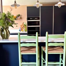 Kitchen island with lime green bar stool and 3 small pendant lights above