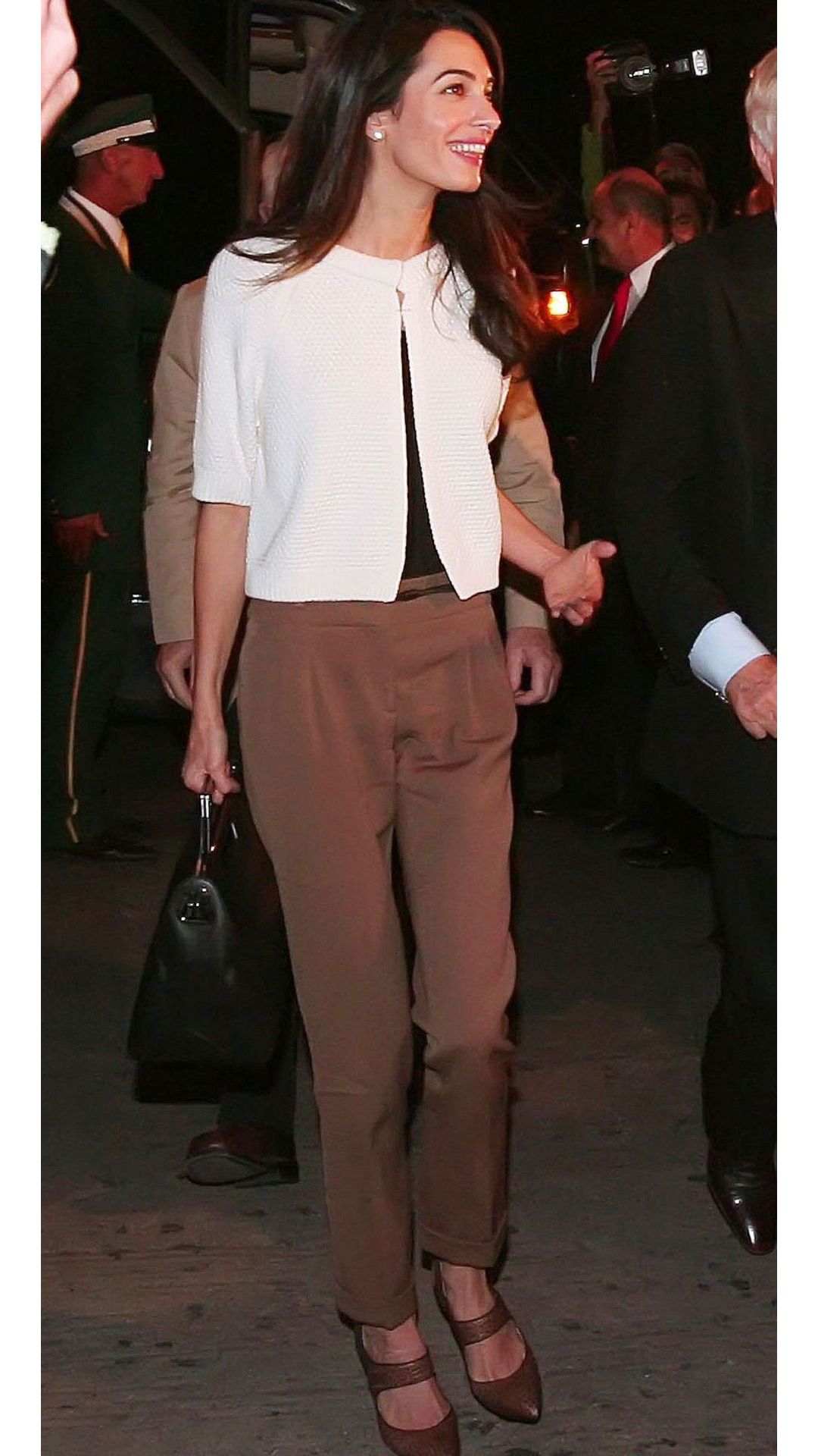 Amal Clooney wearing brown trousers and a cream knit
