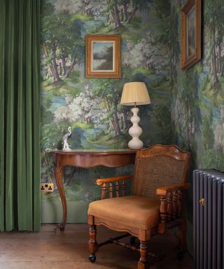 corner in living room with forest/wood style mural green velvet drapes, mahogany armchair and console, lamp, artwork, radiator