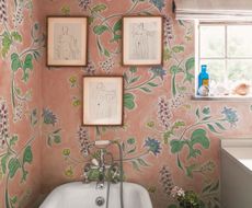 A bathroom with a bright pink botanical wallpaper and three sketched on the wall