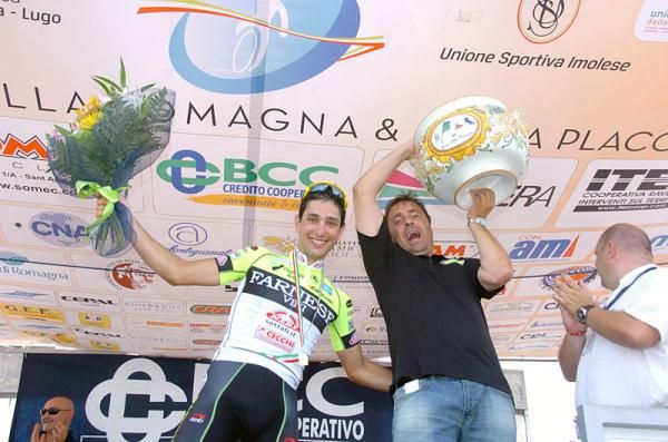 Giro della Romagna winner Oscar Gatto and team manager Luca Scinto celebrate on the podium.