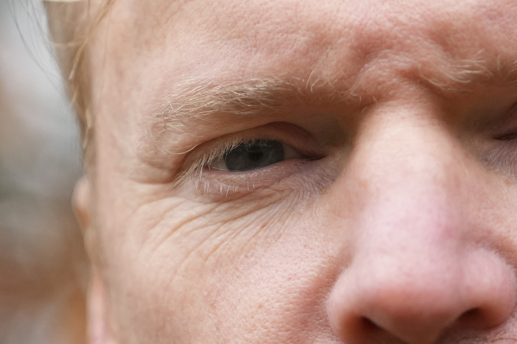 Closeup of the eye in portrait of a man with autumn leaves in the background, taken with the Sony A1 II